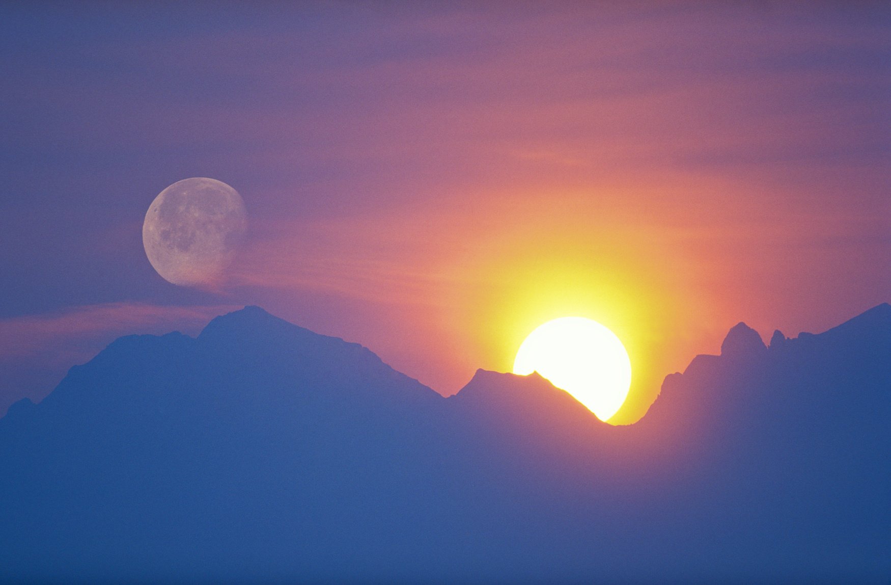 sun and moon behind mountain